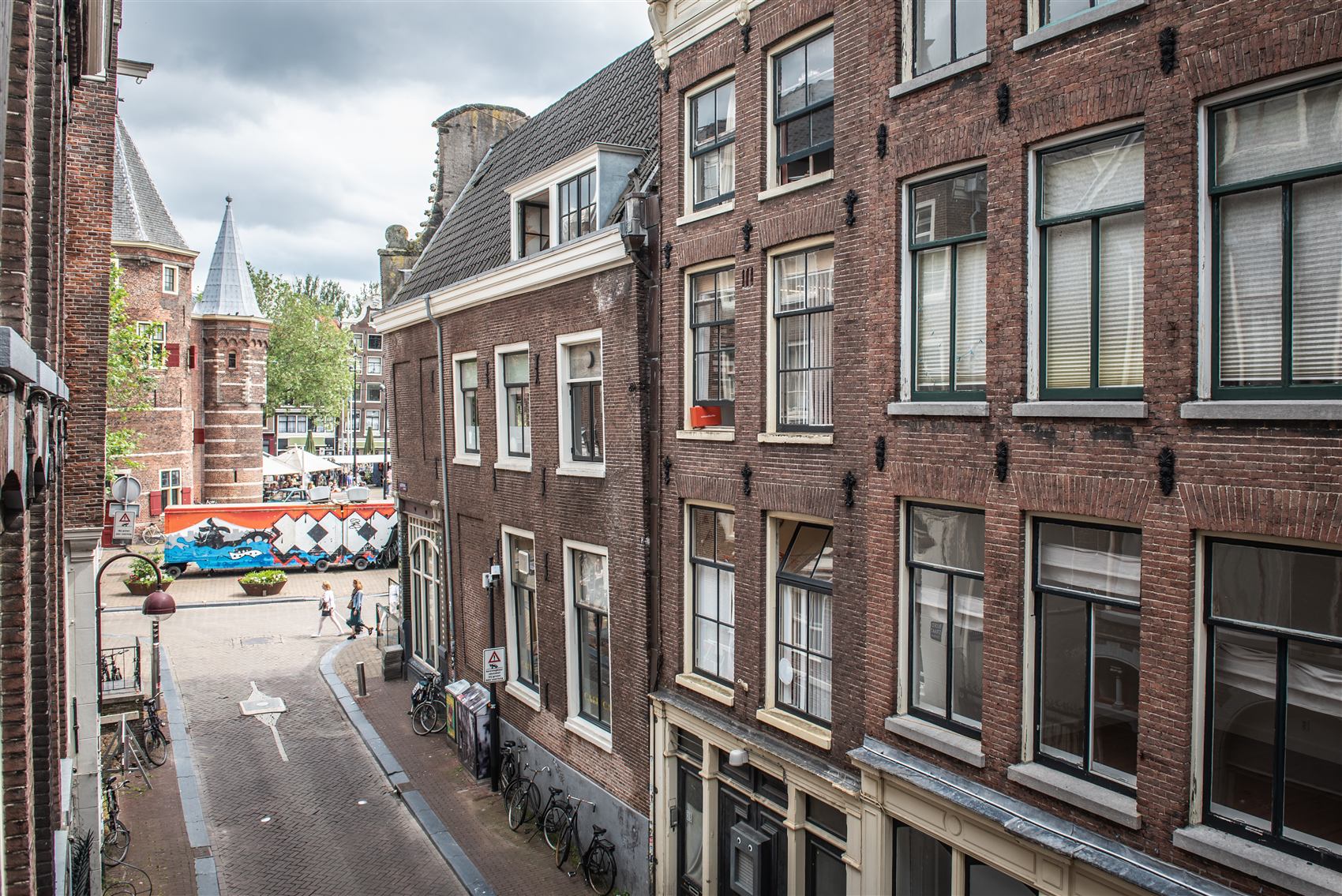 Looking down a narrow canal in the old centre of Amsterdam from an upper window, brick facades on both sides.